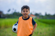 © TheVisualsYouNeed - lifestyle portrait of handsome and happy young boy holding soccer ball playing football outdoors at green grass field smiling cheerful wearing training vest