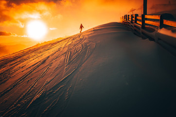 Snowboarder in ski resort. Winter sport photo. Orange sunset light in background. Edit space