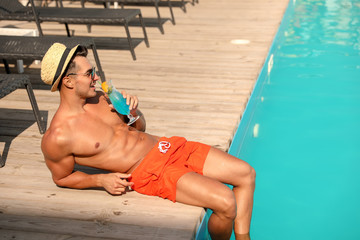 Wall Mural - Young man with cocktail near pool on sunny day