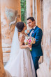 © nataliakabliuk - Sensual wedding married couple, valentines hugging in front of old slavic castle. Wedding day of bride and groom. Man and woman posing near old columns. Wedding photoshoot.
