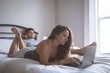 © Wavebreak Media - Couple using laptop and digital tablet in bedroom