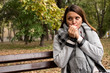 © Natasa - beautiful young woman sits on the bench in the park and tries to warm her hands