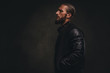 © Fxquadro - Profile of a fashionable bearded male in a black jacket. Isolated on dark textured background.