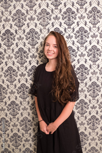 Fotografia, Obraz Portrait of a young woman standing in front of classic 1960s vintage fuzz on foil wallpaper