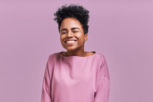 Portrait Of Overjoyed Happiness African American Female, Widely Smiled And Close Eyes, Celebrates Her Success, Poses Against Lavender Background. People, Happiness, Success Concept