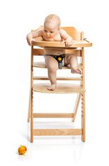 Wall Mural - Cute baby girl looking at peach she dropped while sitting in high chair