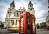 Fototapeta Big Ben - red phone boxes and yellow car passing Saint Paul's Cathedral in London at cloudy day