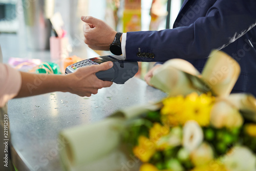 Fotografía Closeup of modern gentleman paying via smartwatch while buying flowers in flower