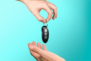 Poster - Hand with a car key on blue background