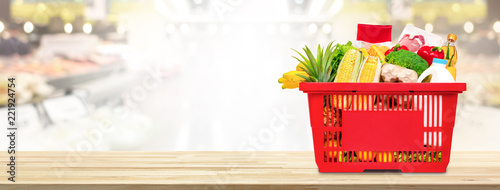 Fotomural Shopping basket full of food and groceries on the table in supermarket