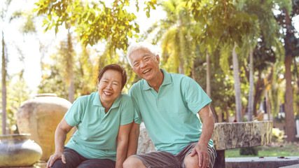 Wall Mural - Happy Asian elderly couple laugh together in green natural park background