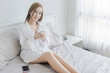 Beautiful young woman drinking coffee sitting on bed in the house.