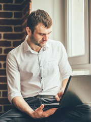 Wall Mural - businessman reads business correspondence on his laptop near the window in the office