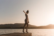 © Angel Ruiz Sanchez - Side view of young caucasian girl dancing on the edge of a dock of a lake in a sunset of a day of summer mountains background
