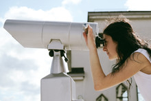 Young Woman Looking Through Sightseeing Binoculars. Close-up Portrait Of Pretty Girl Using A Tower Viewer To Look A Panorama Of City. Vintage, Soft Colors. 