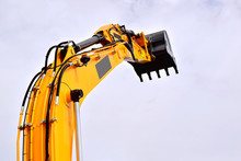 Hydraulic Cylinder Lifting Bucket. Working Equipment Of A Single-bucket Excavator. Yellow. The Background Of The Sky.