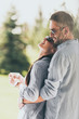 © LIGHTFIELD STUDIOS - side view of happy man in sunglasses embracing girlfriend with coffee cup outdoors