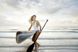 © David Gonzalez - Miami woman at the beach carrying a paddle board at sunrise