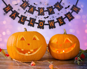 Wall Mural - holidays, halloween and decoration concept - close up of pumpkins on table over lights and party garland background