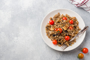 Wall Mural - Buckwheat porridge with mushrooms and cherry tomatoes on a plate. Copy space