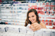© bnenin - Young woman holding cosmetics in her hand in drugstore department of a supermarket.