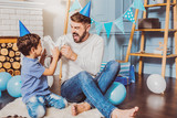 Fototapeta Londyn - Fight robots. Satisfied attractive man shouting while celebrating birthday with son