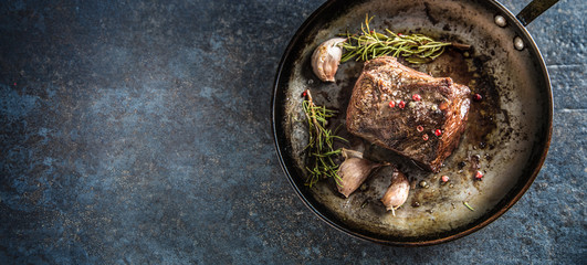 Juicy beef steak with spices and herbs in old pan