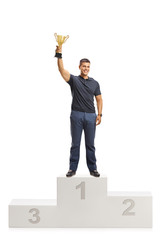 Canvas Print - Young man with a golden trophy standing on a winners pedestal