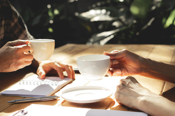 The people holding coffee cup on wooden table in garden with working.