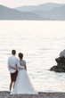 Back view of wedding couple at the beach and looking to the horizon at the sunset, Montenegro