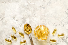 Bunch of omega 3 fish liver oil capsules in silver spoon. Close up of big golden translucent pills in pile. Healthy every day fatty acids nutritional supplement dosage. Top view, flat lay, copy space.