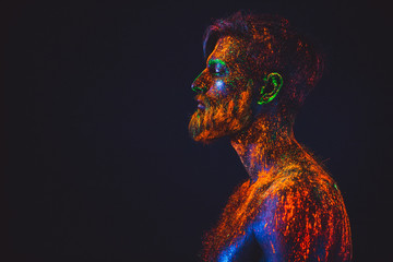 Concept. Portrait of a bearded man. The man is painted in ultraviolet powder.