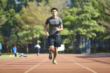 Young Asian Male Athlete Running On Track