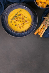 Wall Mural - Pumpkin soup in blue bowl topped with fresh herb