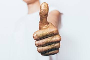 Female hand painted in golden showing thumb up