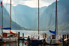 A View Of Lake Hallstatt Or The Sea Bay, Yachts Or Sailing Boats, Mountain Scenery And Sky With Clouds