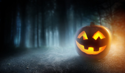 A mysterious and spooky misty halloween evening background with a glowing Jack O Lantern pumpkin.