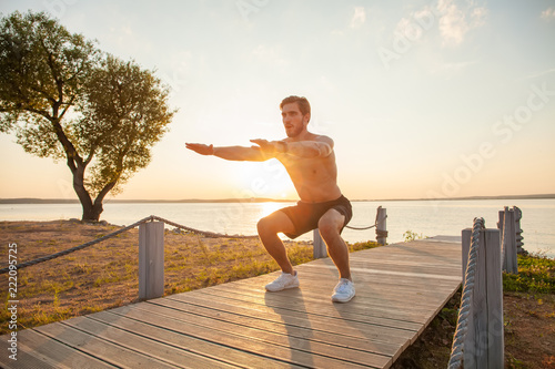 Fotografía Fitness man training air squat exercise on beach outside
