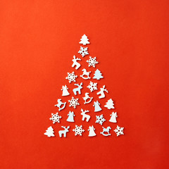 Wall Mural - Christmas card with place for your text. A large Christmas tree on a red background, laid out with wooden figures in the form of a snowflake, a Christmas tree, a horse, a deer, a bell