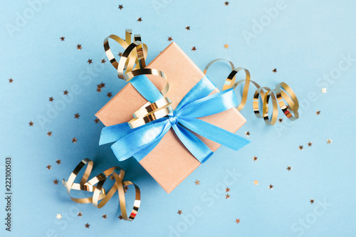 Christmas gift box with golden decorations and sparkles on blue bacground. Gi...