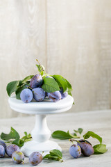 Wall Mural - Many juicy beautiful amazing nice plums on light wooden background. Beautiful food art background