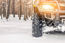 Close-up ATV 4wd Quad Bike In Forest At Winter. 4wd All-terreain Vehicle Stand In Heavy Snow With Deep Wheel Track. Seasonal Extreme Sport Adventure And Trip. Copyspace