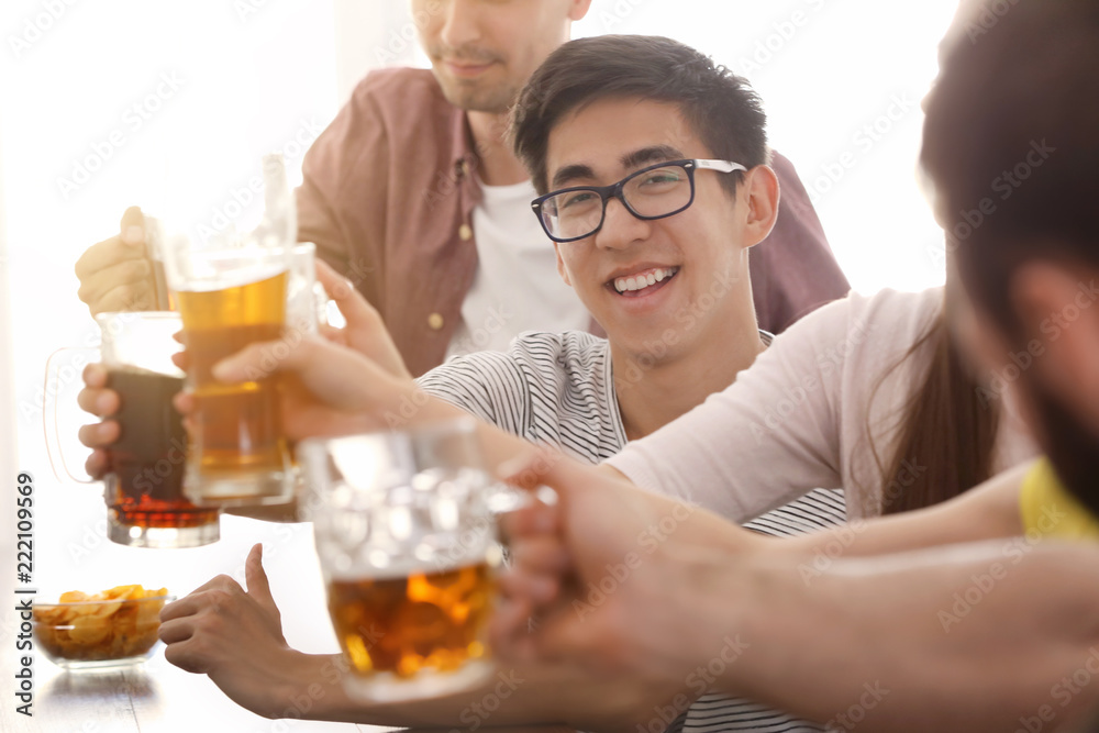 Group of friends clinking glasses with beer in bar