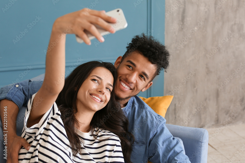 Happy African-American couple taking selfie at home