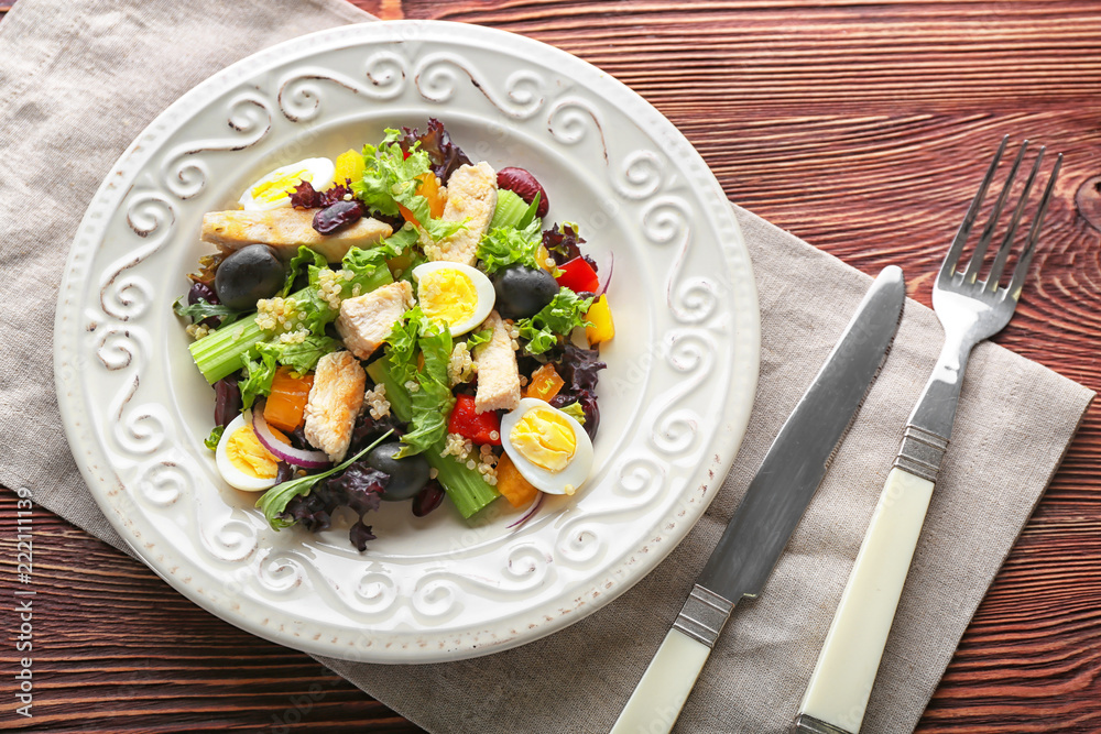 Plate with tasty chicken salad on wooden table