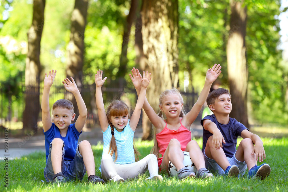 Cute little children sitting on green grass in park