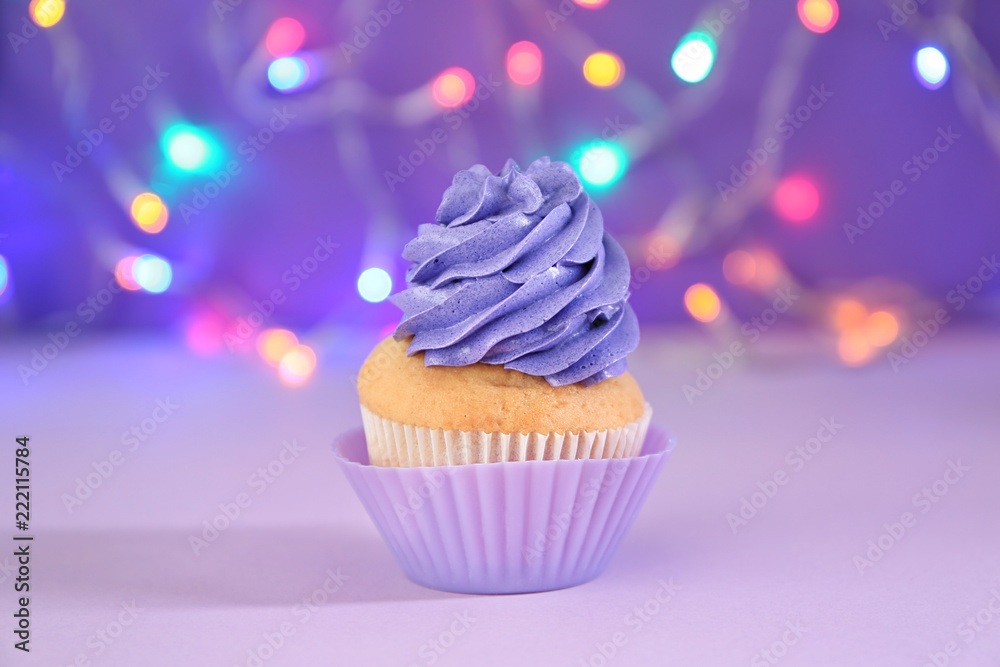 Delicious birthday cupcake against blurred lights