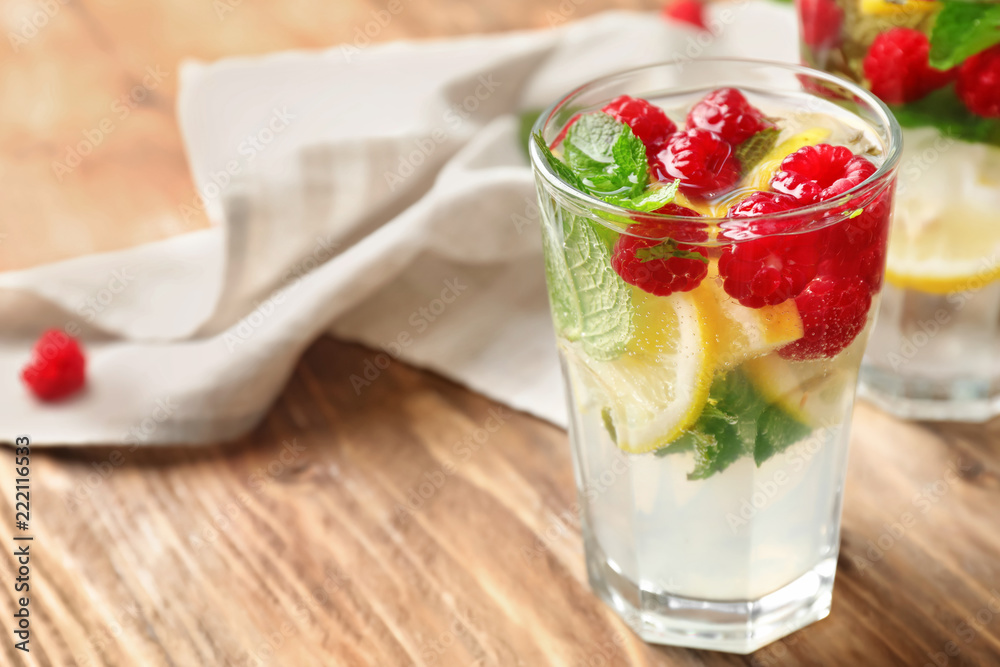 Glass of fresh raspberry mojito on wooden table