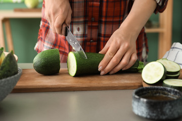 Woman cutting zucchini in kitchen