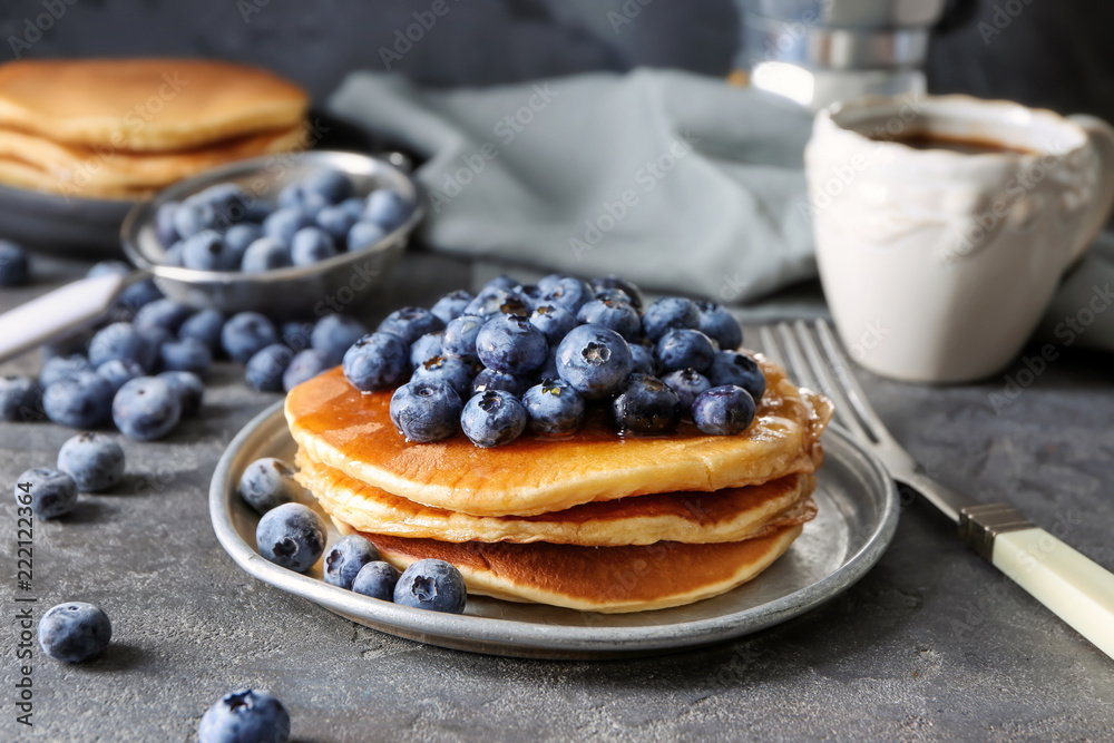 Plate with tasty pancakes and blueberries on dark table
